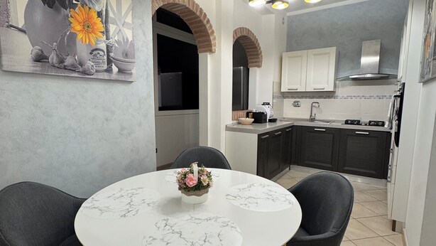 A modern kitchen with a central island, dark cabinetry, and a dining area with a round table and chairs.