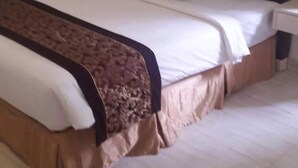 Une chambre d’hôtel avec un grand lit, une table de chevet, une lampe et un tableau encadré au mur.
