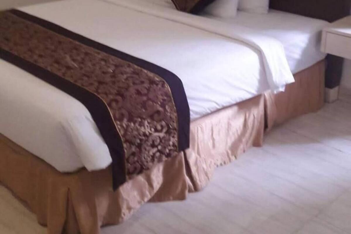 Ein Hotelzimmer mit einem großen Bett, einem Nachttisch, einer Lampe und einem gerahmten Bild an der Wand.