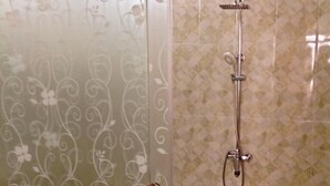 Une douche avec une porte en verre et un pommeau de douche.