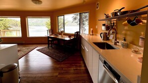 A modern kitchen with a dining area, large windows, and a dishwasher. - Shangrila Luxury Waterfront Panorama Suite | Oceanfront Seating & Beach Access (Pender Island)