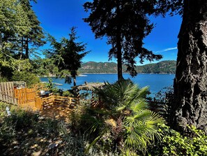 A wooden deck with a view of a lake and mountains. - Shangrila Luxury Waterfront Panorama Suite | Oceanfront Seating & Beach Access (Pender Island)