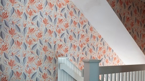Un escalier orné d’un papier peint à motifs représentant des oiseaux et des feuilles.