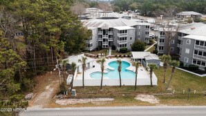 A multi-story residential building with a swimming pool surrounded by palm trees. - Calabash ready
 (Calabash)