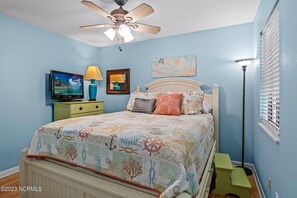 A bedroom with a bed, a ceiling fan, a TV, a lamp, and a window with blinds. - Calabash ready
 (Calabash)
