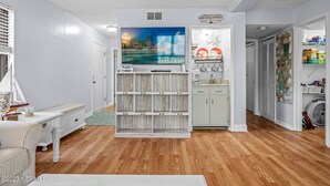 A living room with a wooden floor, a white sofa, a TV on a wooden stand, and a painting above the stand. - Calabash ready
 (Calabash)