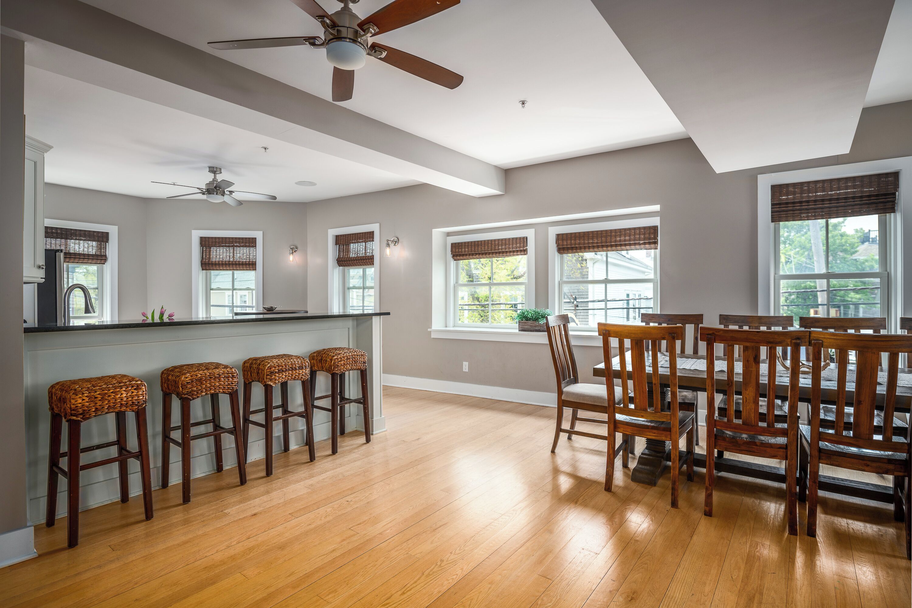 A spacious kitchen with wooden flooring, a central island, and a dining area with wooden chairs and a table.