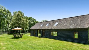 A log cabin with a large lawn, a dining area with a table and chairs, and a covered patio.