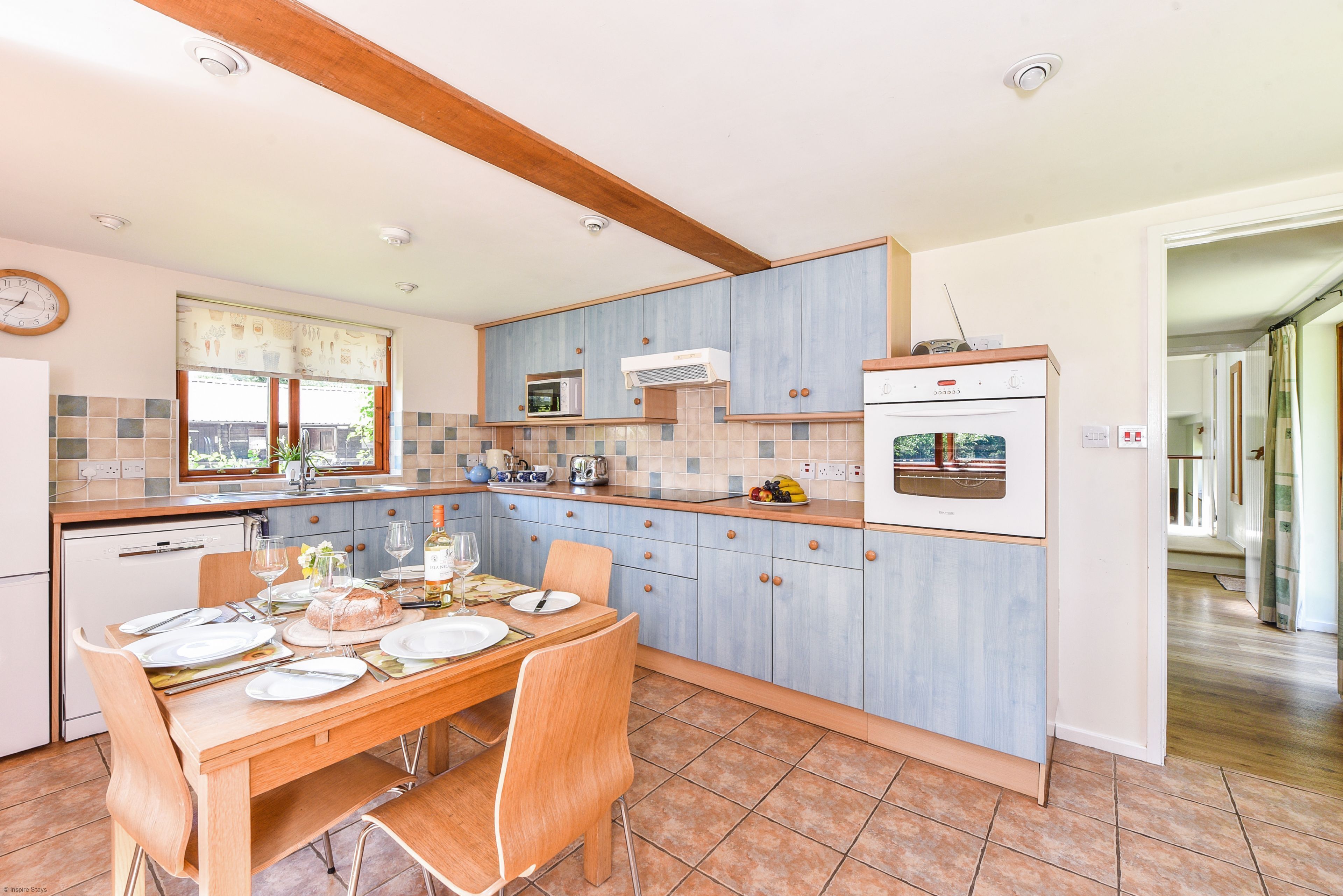 Una cocina con armarios azules, una mesa de comedor de madera y un refrigerador blanco.