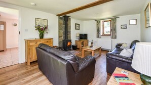 A cozy living room with a fireplace, leather sofas, wooden furniture, and a television.