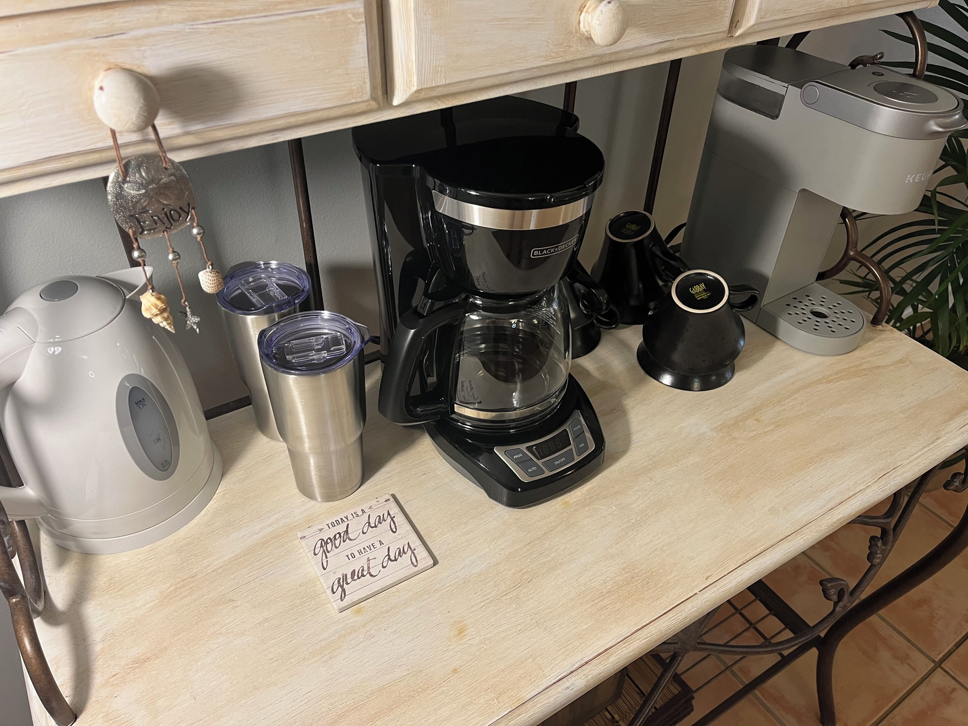 A kitchen counter with a coffee maker, a kettle, and a mug.