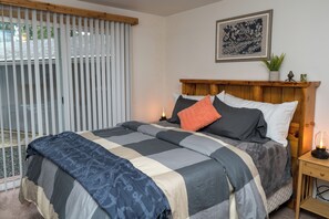 A neatly made bed with a patterned bedspread, a wooden headboard, and a bedside table with a lamp. -  Cozy and Dog friendly retreat by Relaxing Creek & Hot tub by Lake Cushman (Hoodsport)