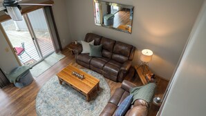 A living room with a brown leather sofa, a wooden coffee table, and a floor lamp. -  Cozy and Dog friendly retreat by Relaxing Creek & Hot tub by Lake Cushman (Hoodsport)