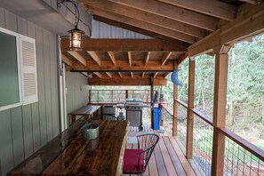 A wooden deck with a grill, a table, and a chair. -  Cozy and Dog friendly retreat by Relaxing Creek & Hot tub by Lake Cushman (Hoodsport)