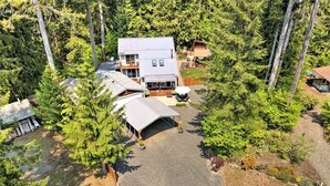 A two-story house with a covered patio and a driveway. -  Cozy and Dog friendly retreat by Relaxing Creek & Hot tub by Lake Cushman (Hoodsport)