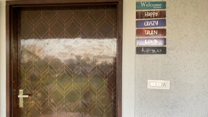 A door with a geometric pattern and a welcome sign with words like "Happy," "Crazy," and "Gun."
