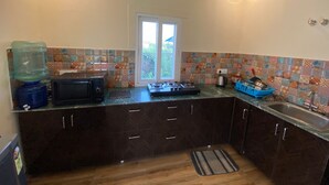 A compact kitchen with dark cabinets, a microwave, a gas stove, a sink, and a window with a view.