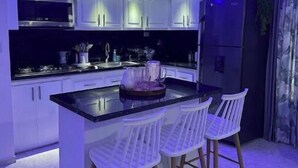 Una cocina moderna con armarios blancos, encimera negra y una isla central con taburetes de bar.