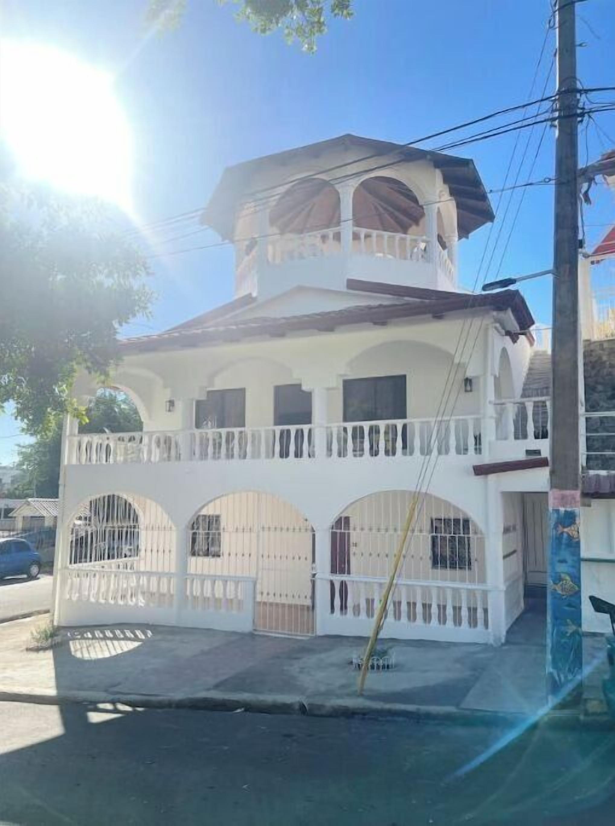 Un immeuble de deux étages doté d’un balcon, d’une entrée fermée par un portail et surplombant un ciel dégagé.