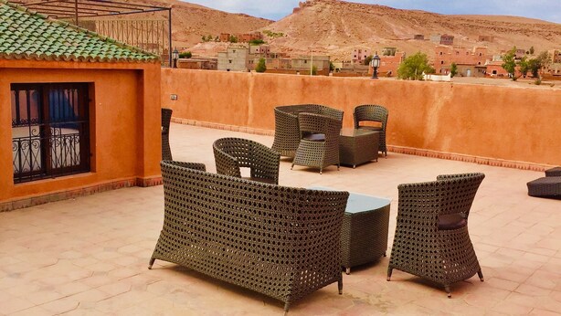 An outdoor patio with wicker furniture and a view of a desert landscape. - Riad Ait Ben Haddou (Aït Benhaddou)