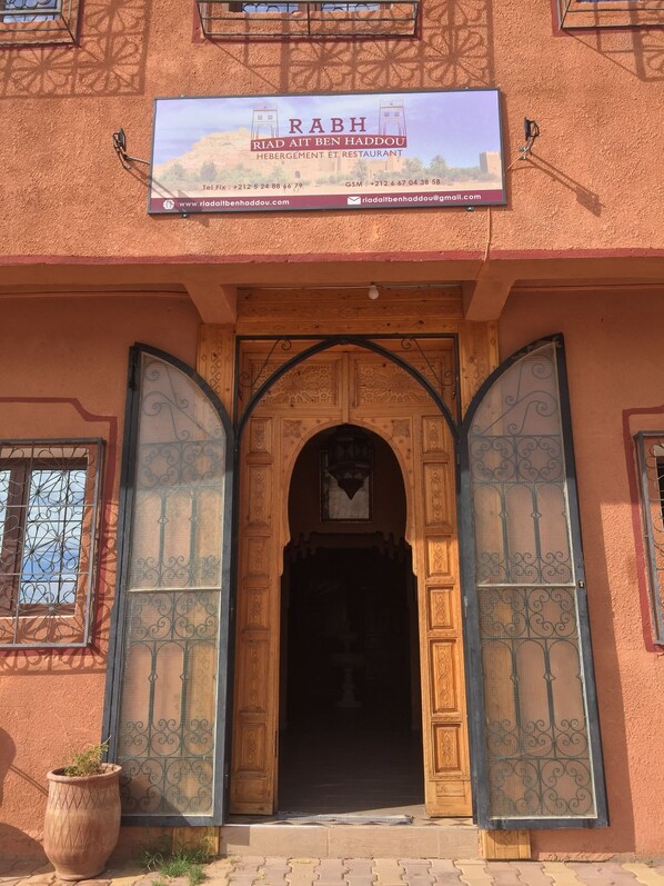 A building entrance with a sign reading "RABH RIAD AIT BEN HADDOU HEBERGEMENT ET RESTAURANT."