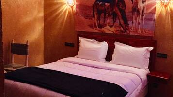 Habitació d'hotel amb un llit, un capçal, una taula de nit i un quadre penjat a la paret.