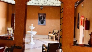 A room with a stone wall, a white fountain, and a patterned floor. - Riad Ait Ben Haddou (Aït Benhaddou)