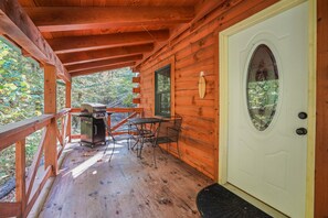 A wooden cabin with a porch, a dining table, chairs, and a grill. - Creekside Serenity | Hocking Hills, Creek, Hot Tub (Logan)