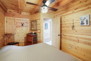 A cabin interior with a bed, dresser, mirror, and a ceiling fan. - Creekside Serenity | Hocking Hills, Creek, Hot Tub (Logan)