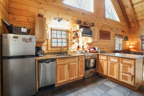 Una cocina estilo cabaña de madera con refrigerador, lavavajillas, estufa y encimeras de granito.