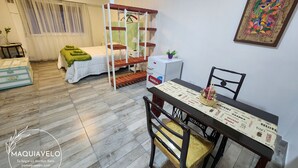 A room with a bunk bed, a dining table with chairs, a small white cabinet, and a colorful wall decoration. - Amplio y Confortable Monoambiente en el Centro de la Ciudad. A (Buenos Aires)