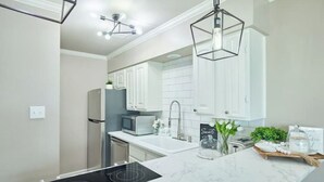 Une cuisine moderne avec des meubles blancs, une plaque de cuisson à induction noire et un plan de travail en marbre.