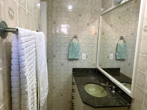 A bathroom with patterned tiles, a sink, and two towels hanging on hooks. - Cobertura Triplex Guarujá (Guarujá)