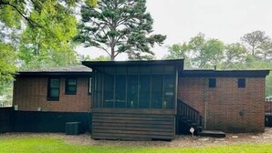 Een twee verdiepingen tellend bakstenen huis met een groot raam op de begane grond en een trap die naar de tweede verdieping leidt.