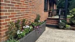 Een bakstenen gebouw met een overdekte veranda en een bloembak met bloemen.