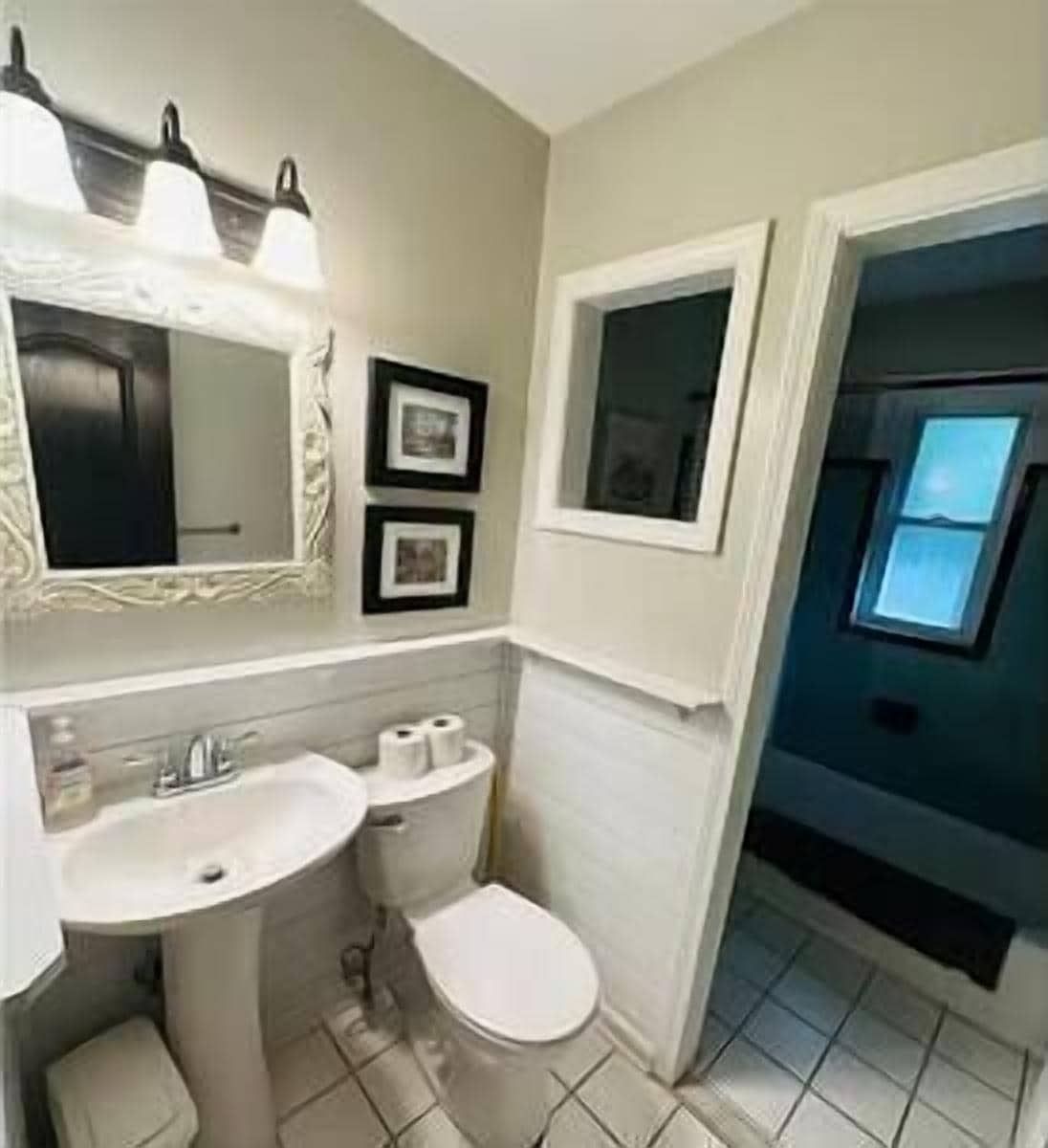 A bathroom with a sink, toilet, and a window.