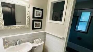 A bathroom with a sink, toilet, and a window.