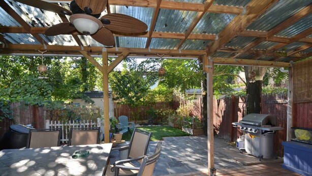 Une terrasse couverte avec une table et des chaises, un barbecue et une plateforme en bois.
