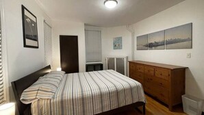 Une chambre à coucher avec un lit, une commode, un radiateur et une œuvre d’art accrochée au mur.