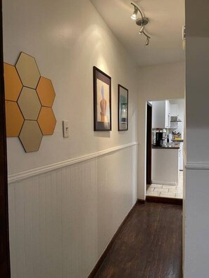 A hallway with a white wainscoting, a hexagonal wall decoration, and framed artwork.