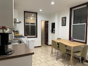 A compact kitchen with a coffee maker, sink, and dining table with chairs.