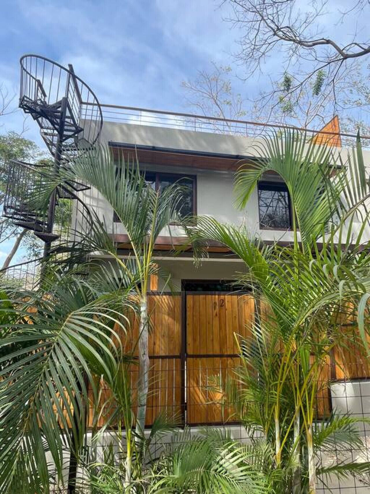 A modern two-story house with a wooden balcony and a spiral staircase.