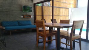 Un comedor con una mesa y sillas de madera, un sofá azul y un televisor montado en la pared.