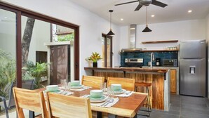 Un comedor con mesa y sillas de madera, una cocina con electrodomésticos modernos y un ventilador de techo.