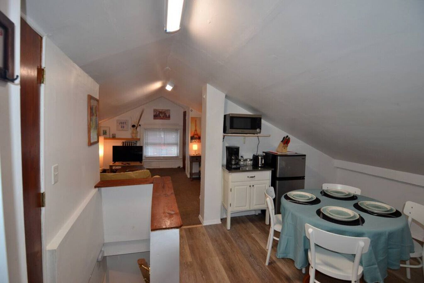 A compact kitchen with a dining area, a microwave, a refrigerator, and a small window.