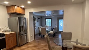 A modern kitchen with stainless steel appliances, wooden cabinets, and a dining area with a glass table and chairs.
