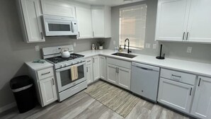 Une cuisine moderne avec des meubles blancs, une cuisinière, un four à micro-ondes et un évier.