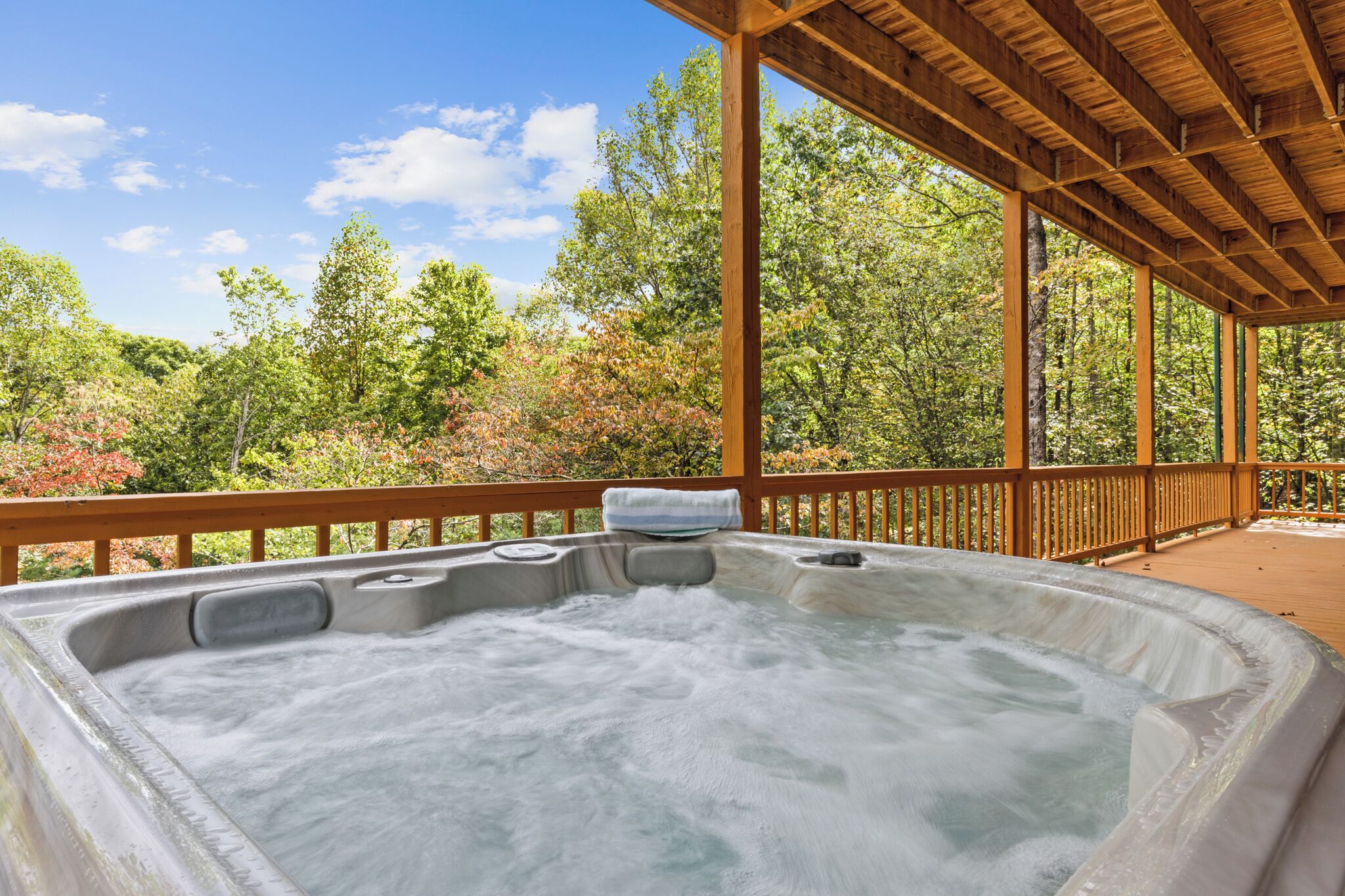 Un jacuzzi bajo una pérgola de madera con vistas a un área boscosa.