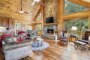A spacious living room with a fireplace, wooden furniture, and large windows.