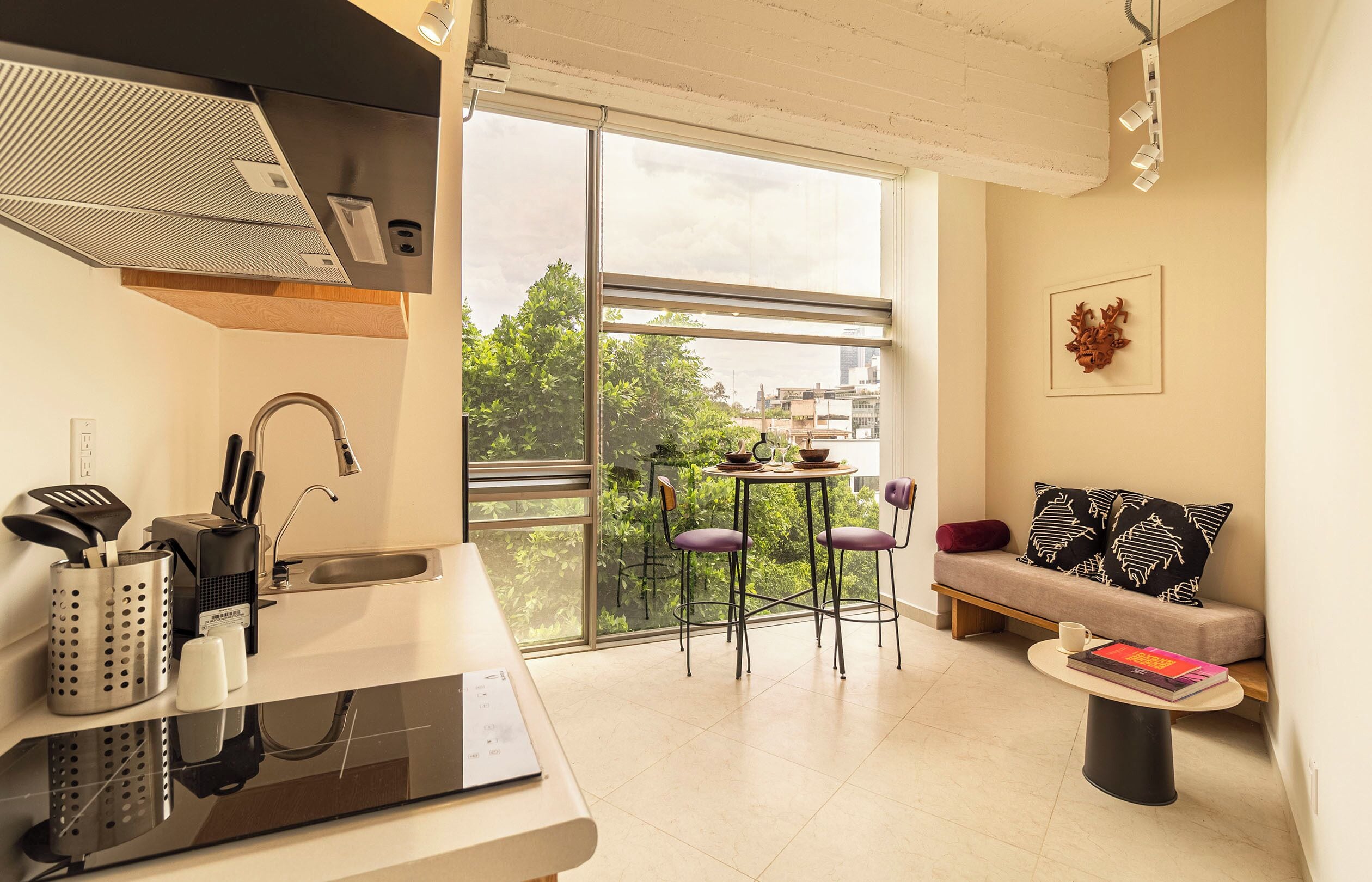 Una cocina moderna con estufa integrada, un lavaplatos y un ventanal con vistas a un balcón lleno de plantas.
